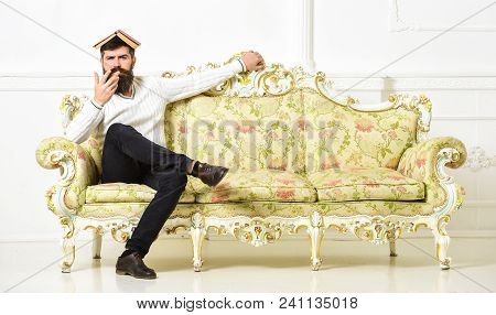 Macho Sits With Open Book On Head, Like Roof. Overstudy Concept. Man With Beard And Mustache Sits On
