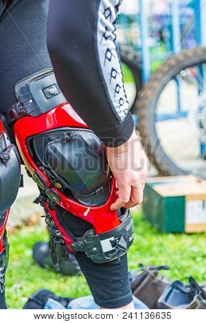 Man Puts Protection On His Knees For Motorsport, Black Red, Close-up