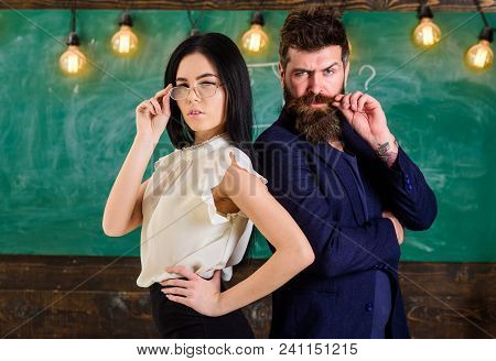 Man With Beard And Teacher In Eyeglasses Stand Back To Back, Chalkboard On Background. Lady And Hips