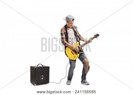 Full length portrait of a teenage boy playing electric guitar connected to an amplifier isolated on white background