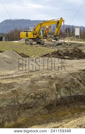 Some Excavators At A Loamy Construction Site
