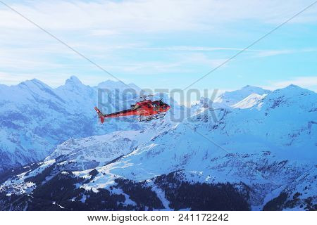 Maennlichen, Switzerland - December 31, 2013: Red Helicopter Flying Over Maennlichen Swiss Alpine Mo
