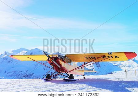 Maennlichen, Switzerland - December 31, 2013: Yellow Airplane In Mountain Alpine Peaks In Maennliche