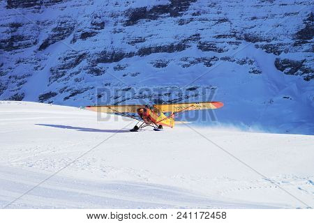Maennlichen, Switzerland - December 31, 2013: Yellow Airplane In Mountain Alps Peaks In Maennlichen 