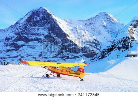 Maennlichen, Switzerland - December 31, 2013: Yellow Airplane At Mountain Alpine Peaks In Maennliche