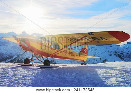Maennlichen, Switzerland - December 31, 2013: Yellow Airplane In Mountain Peaks In Maennlichen In Wi