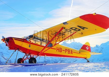Maennlichen, Switzerland - December 31, 2013: Yellow Airplane In Mountain Alpine Peaks In Maennliche