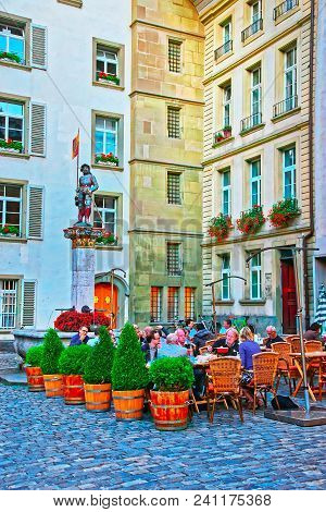 Bern, Switzerland - August 21, 2013: People At Sidewalk Cafe Near Banneret Fountain On Rathausplatz 