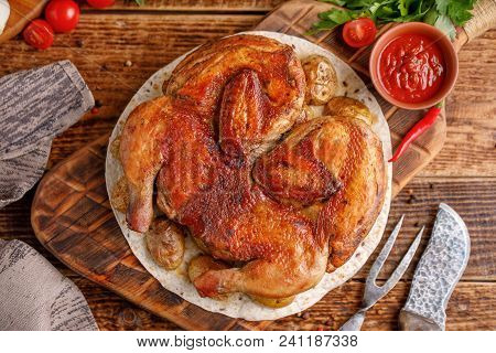 Chicken Of Tobacco With Garnish Of Baked Young Potatoes. Still Life On A Wooden Background With Text