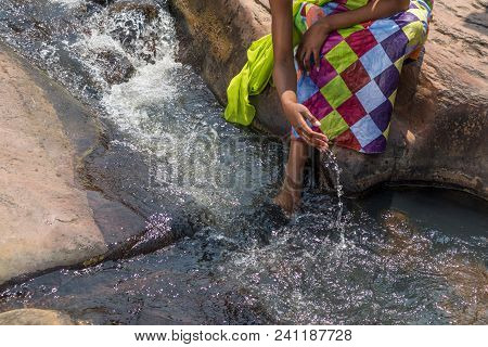 Woman In African Outfit On The Verge Of Fluent River. Interacting With Water. Angola.