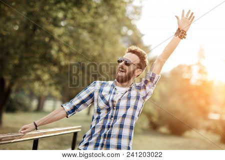 Happy Celebrating Bearded Man Posing With Hands Upin The Park