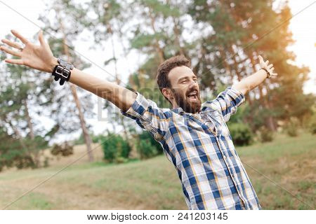 Happy Celebrating Bearded Man Posing With Hands Upin The Park