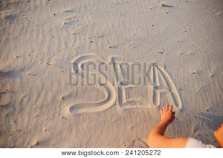 A Young Woman Writes In The Sand The Word Sea