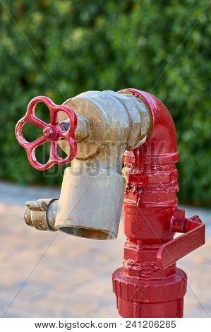 Red Old Fireplug With White Valve Against Of A Wall Background.