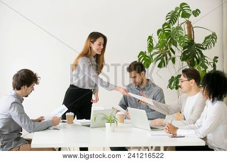 Young Woman Leader Boss Giving Team Members Documents For Review Or Consideration, Smiling Businessw