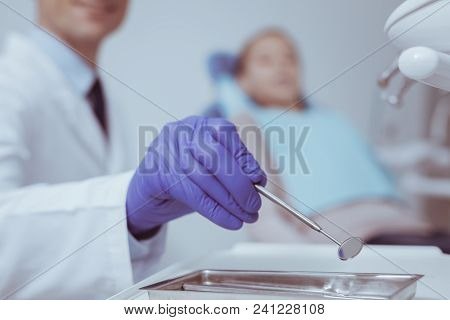 Additional Tool. Selective Hand Of Male Hand Wearing Blue Gloves And Selecting Mouth Mirror