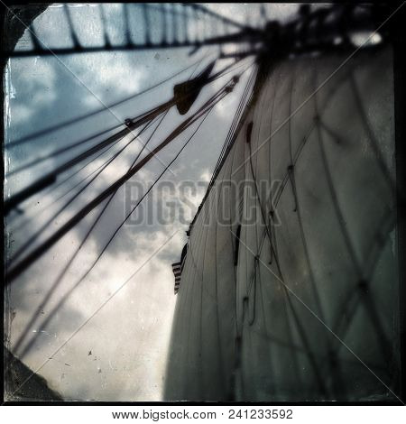Looking up to antique sailing ship sails and rigging on the open sea - vintage tintype effect