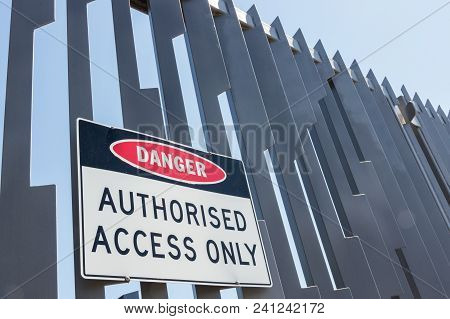 Warning Sign Against Unauthorised Access On A High Steel Security Fence.