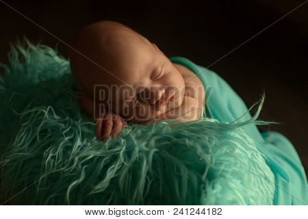A Little Child In A Green Diaper Lies On A Black Background