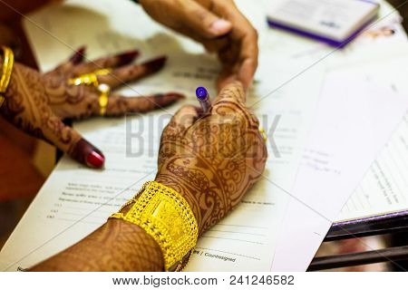 A Newly Married Indian Bengali Wife With Golden Ornament And Blacelet Signing Marriage Registration
