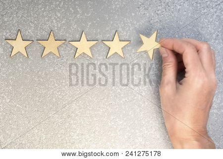 Five Wooden Stars And Hand Putting The Last One To Increase Rating On A Silver Background, Top View 