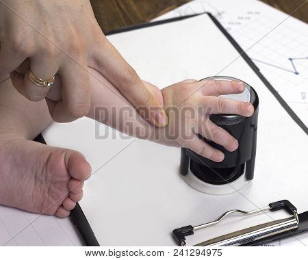 Child's Hand Puts A Seal On A White Sheet