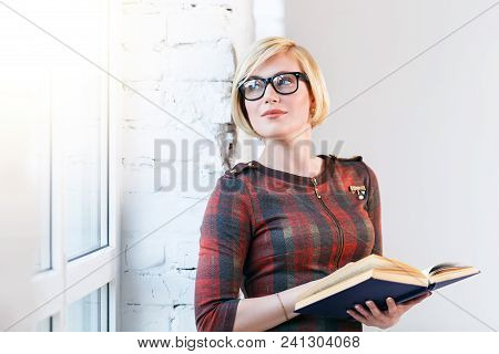 Pretty Intelligent Blonde Woman Wears Eyeglasses And Red Dress Reading Book Near Wide Window In Lagh