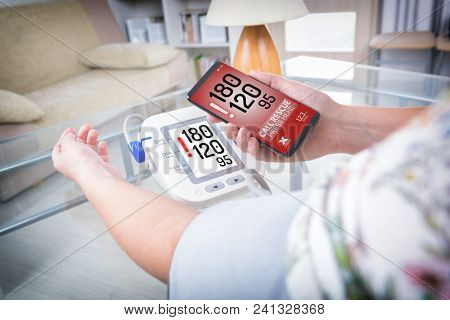 Woman measuring blood pressure at home and using simple user-friendly smart phone application to call rescue team to prevent heart attack