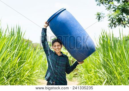 Young Asian Farmer Carry Blue Water Tank (fermented Water Tank) For Watering In Napier Grass Field