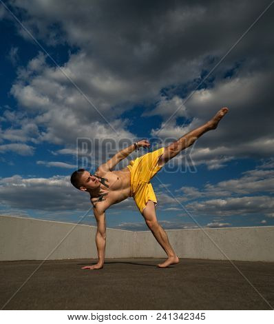Tricking On Street. Martial Arts. Man Kick With Hand Support Barefoot. Shooted From Bottom Foreshort