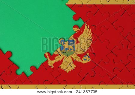 Montenegro Flag  Is Depicted On A Completed Jigsaw Puzzle With Free Green Copy Space On The Left Sid