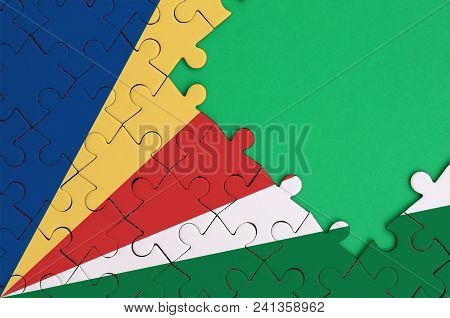 Seychelles Flag  Is Depicted On A Completed Jigsaw Puzzle With Free Green Copy Space On The Right Si