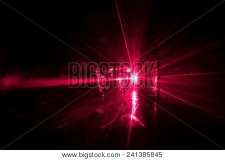 Two Glasses Of Vodka With Bottle On Dark Foggy Club Style Background With Glowing Lights (laser, Sto