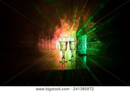 Two Glasses Of Vodka With Bottle On Dark Foggy Club Style Background With Glowing Lights (laser, Sto