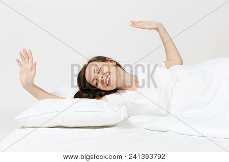 Calm Young Woman Lying In Bed With White Sheet, Pillow, Blanket On White Background. Smiling Beauty 