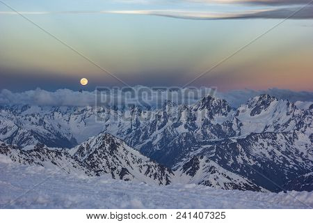 Snowy Caucasus Mountains With Glaciers At Sunset From Elbrus Slopes With Stones And Clouds On Blue S