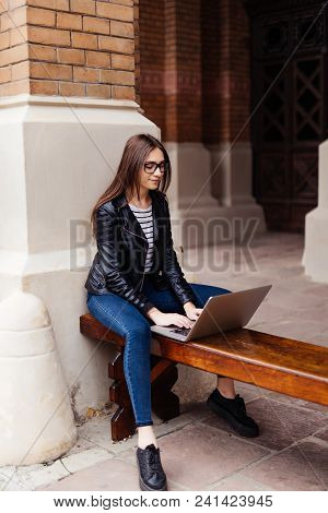 Smiling Student Girl Sitting On Bench In Park, Working With Laptop And Taking Notes, Preparing For E
