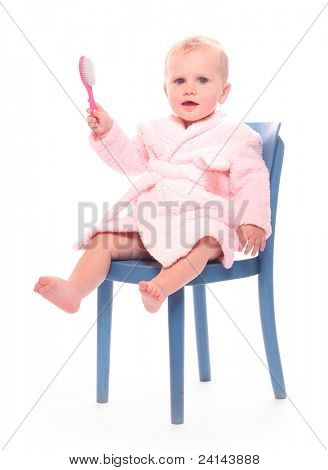 Heureux enfant habillée en robe de bain avec brosse à cheveux.