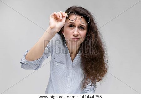 Young Girl With Glasses On A Gray Background. Portrait Of A Young Beautiful Girl. A Charming Girl In