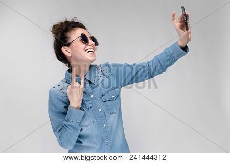 Young Girl In Round Glasses On A Gray Background. Portrait Of A Young Beautiful Girl. Charming Girl 