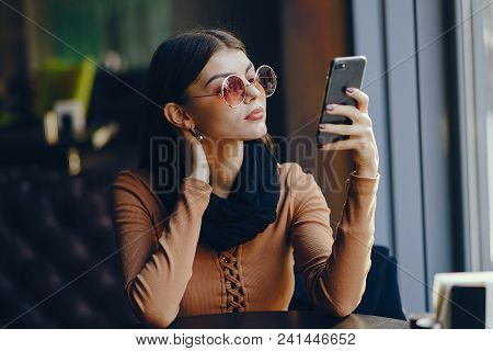 Brunette Girl Using Her Cell Phone While Sitting At A Rastaurant For Lunch