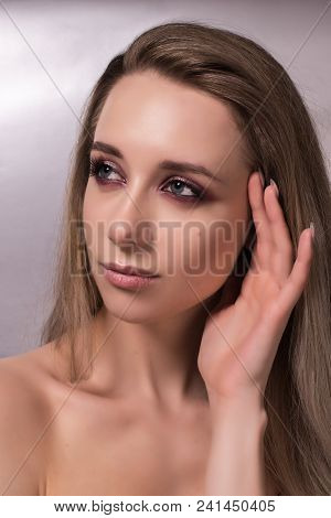 Beautiful Young Girl With Bright Pink Make-up And Combed Hair On A Gray Background.