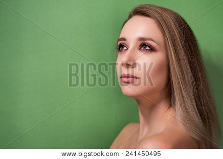 Beautiful Young Girl With Bright Pink Make-up And Combed Hair On A Green Background.