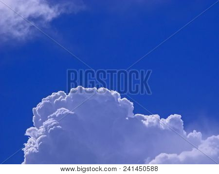 White, Whirling Cloud On A Blue Sky. Edge And Folds Emphasize Sharp, Sunny Light.
