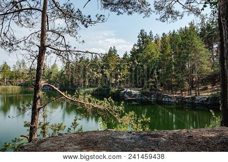 Picturesque Landscape With A Lake In The Middle Of A Coniferous Forest In Korostyshiv Quarry, Zhytom