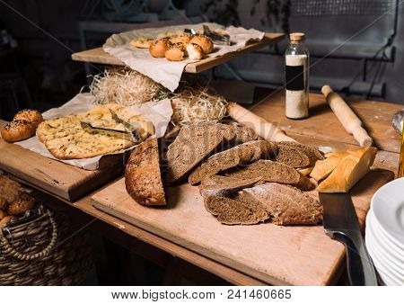 Assortment Of Different Kind Of Cereal Bakery: Bread, Pasties, Buns, Pretzel And Croissant On Old Wo