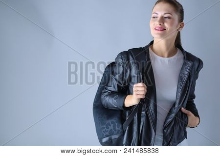 portrait of beautiful young brunette woman in stylish black jacket on gray.