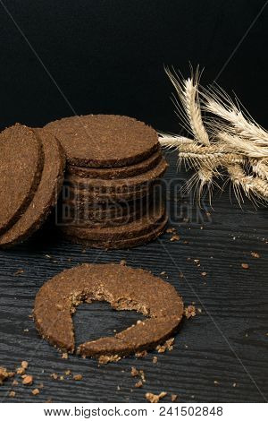 Round Slice Gallets Of Black Bread With A Cut In The Shape Of A Heart On Dark Wooden Background. Vie
