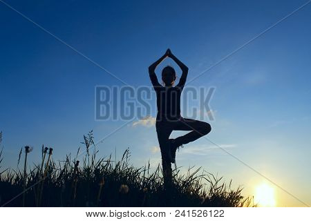 Teenage Girl In A Balancing Yoga Position.  Young Girl In Tree Pose Position, Outdoors.