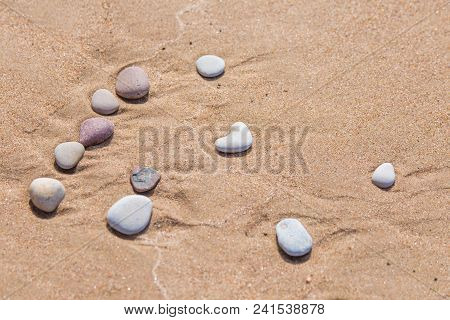 Beautiful Smooth Sea Stones In The Sands Of The Beach. Closeup Photo Of Stone Textures And Shapes.